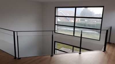 Garde-corps intérieur en acier noir bordant une mezzanine devant une verrière