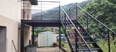 Escalier extérieur en acier et terrasse sur pilotis, devant la montagne