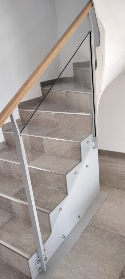 Garde-corps en verre et acier le long d'un escalier intérieur en pierre